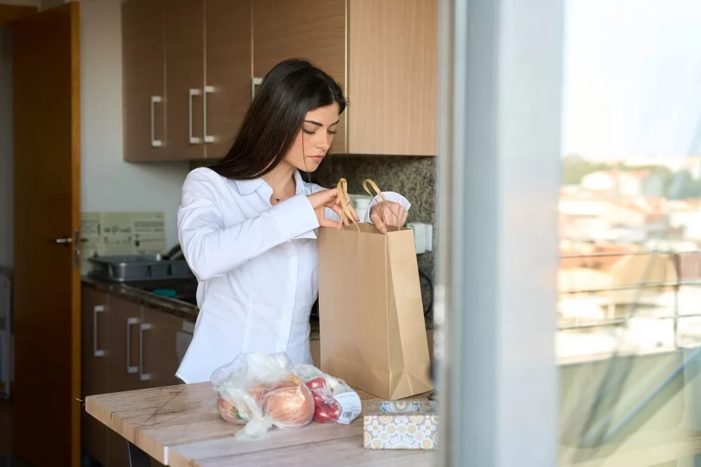 Woman unpacking groceries in kitchen.